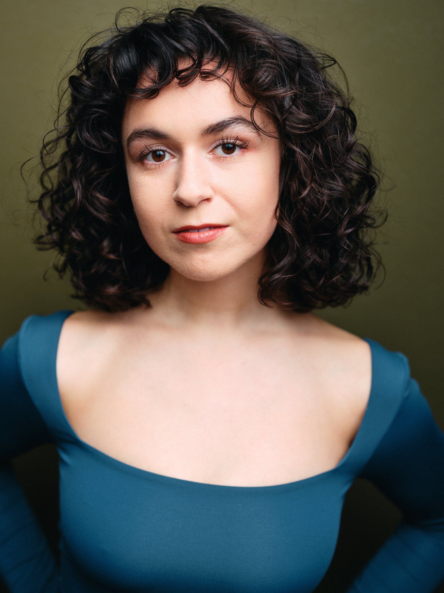 Headshot of Josie Altucher in a teal top against an olive background